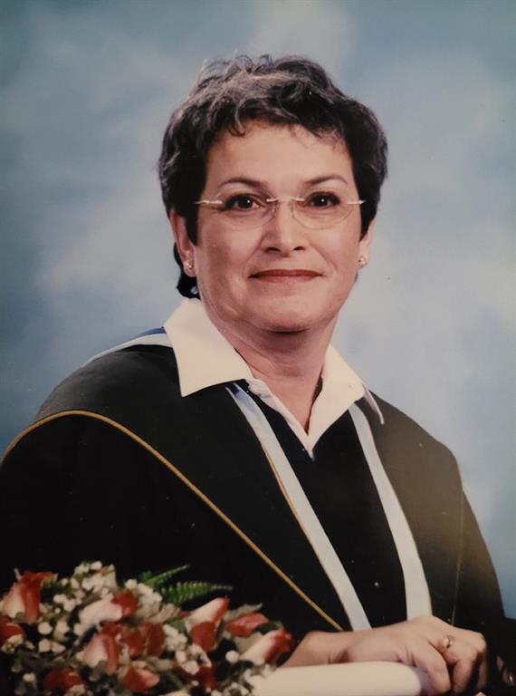 Elizabeth Gunner smiles for a university graduation photo in front of a blue background.